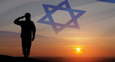 A solider saluting in front of a sunset with the Israeli flag in the background